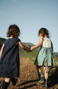 Due bambine si tengono per mano mentre camminano per le colline