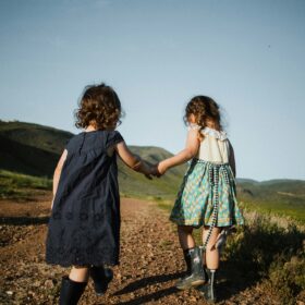 Due bambine si tengono per mano mentre camminano per le colline